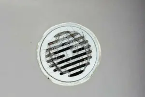 Drain cover with hair and debris, illustrating plumbing maintenance challenges relevant to homeowners.
