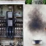 Electrical panel showing switches and wiring, with a blackened spot indicating damage in a home.