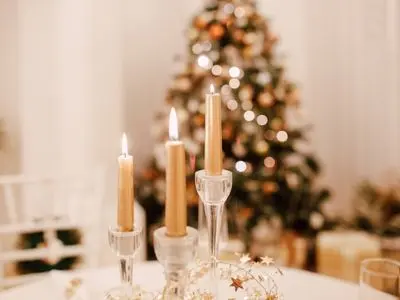 Elegant Christmas candles on a table with a festive tree in the background, enhancing holiday decor and creating a warm atmosphere.
