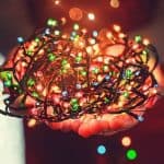 Hands holding colorful Christmas lights, showcasing vibrant holiday decorations for electrical services.