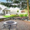 Metal fire pit in a landscaped garden with a residential house, showcasing The Meridian Company's home service environment.
