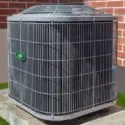 Air conditioning unit on concrete platform with metal grate, green light, against brick wall in Lansing, MI.