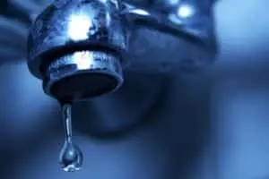 Leaky faucet with water droplet illustrating plumbing maintenance and the importance of professional repair services.