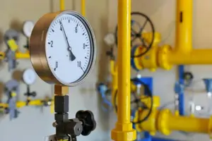 Pressure gauge on plumbing system with yellow pipes, illustrating plumbing maintenance and water pressure management for homeowners.