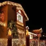 House decorated with holiday lights, visible Christmas tree, and white picket fence, showcasing home service solutions.