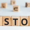 Wooden blocks spelling 'STOP' on a neutral background, emphasizing home comfort and HVAC safety tips.