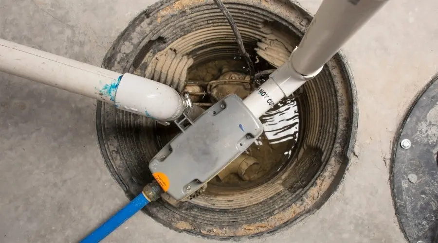 Sump pump installation in a basement, featuring pipes and a pump submerged in water, illustrating essential home protection against flooding.