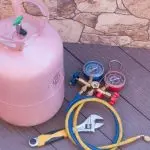 Refrigerant tank with pressure gauges and hoses for air conditioning maintenance, highlighting the importance of proper refrigerant handling and maintenance.