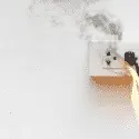 Electrical outlet with smoke and flames, illustrating common electrical hazards in homes.