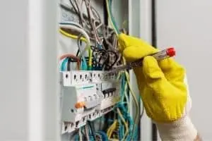 Electrician inspecting electrical panel with wires and circuit breakers, highlighting safety and upgrades for new appliance installations.