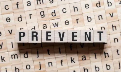 Wooden blocks spelling "PREVENT" on a background of lettered tiles, emphasizing the importance of preventive maintenance for heaters and plumbing systems.