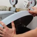 Hands adjusting a mechanical device with gauges during plumbing maintenance at City Plumbing, a plumbing service provider.