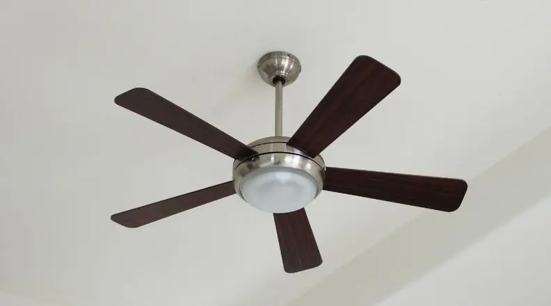 Ceiling fan with dark wood blades and light illustrating energy-saving cooling tips
