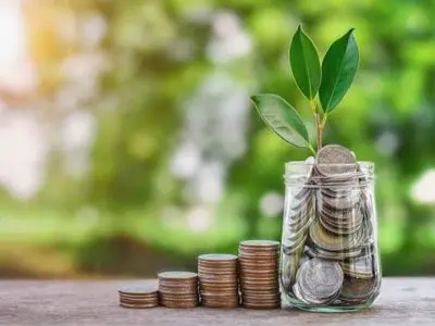 Jar of coins with a small plant growing from the top, symbolizing savings and investment in energy-efficient HVAC systems.