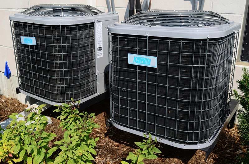 HVAC units from Keeprite installed outdoors, surrounded by greenery, highlighting maintenance and replacement services for home air conditioning systems.