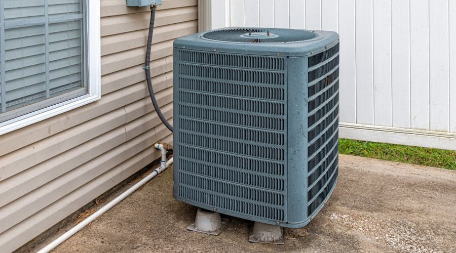 Air conditioning unit outside a home, emphasizing the importance of AC maintenance for summer efficiency and reliability.