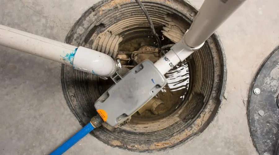 Sump pump system installed in a sump pump basin, featuring discharge pipes and water accumulation, illustrating plumbing solutions for basement flooding prevention.