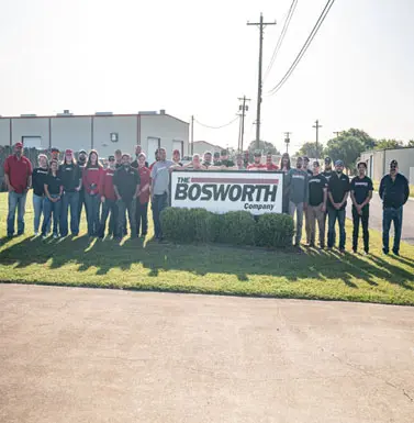Group of employees from The Bosworth Company standing in front of their sign, showcasing the family-owned business's commitment to community service in Kerrville, Texas.