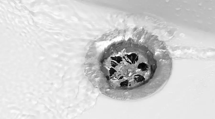Water flowing into a metal drain, illustrating the importance of professional drain cleaning for preventing clogs and plumbing issues.