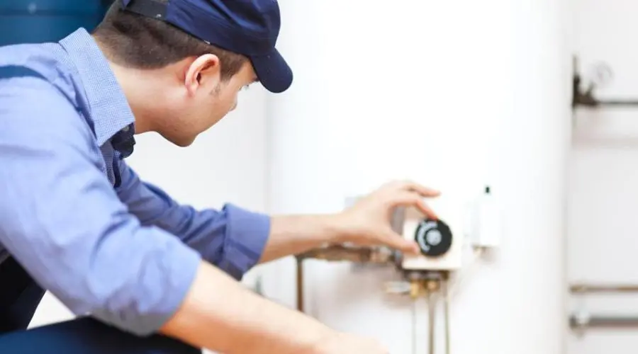Technician adjusting water heater controls in a residential area for Maxwell-White Plumbing services.
