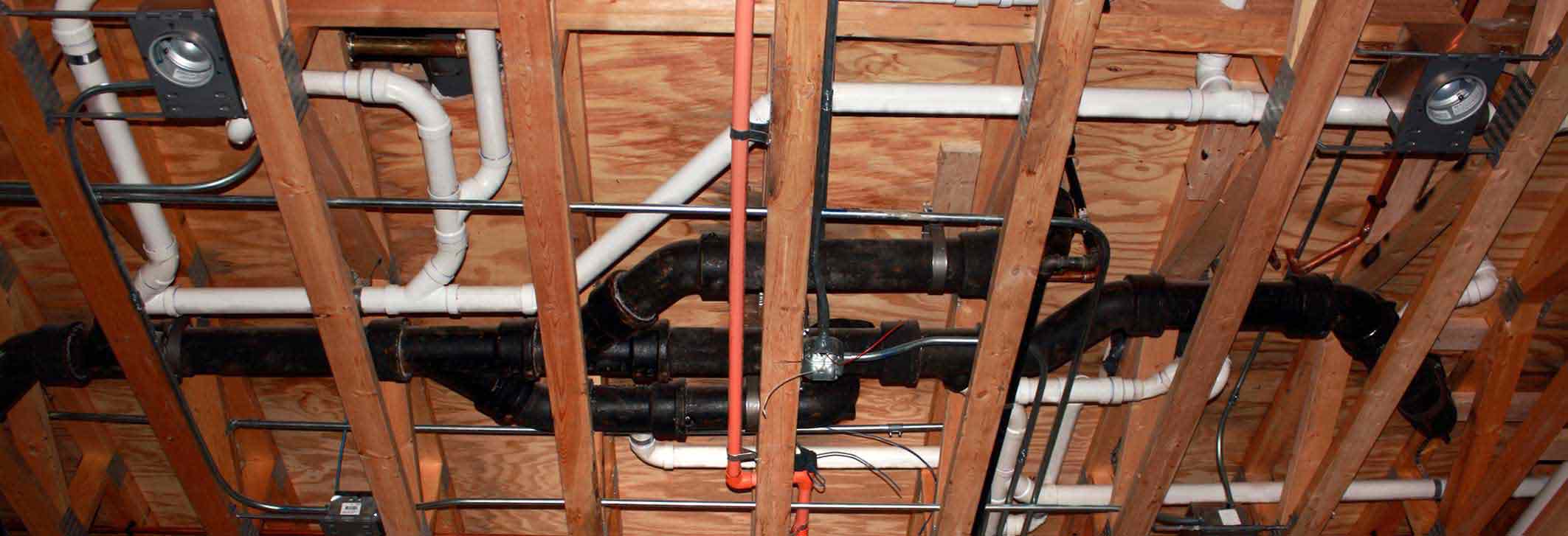 Plumbing infrastructure installation in new construction, featuring black and white pipes and wooden framing, relevant to Maxwell-White Plumbing's services in La Crosse, WI.