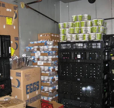 Food storage area with stacked boxes of eggs and containers, highlighting Maxwell-White Plumbing's food drive for local families in need.