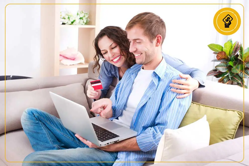 Couple smiling while using a laptop to explore financing options for plumbing services, emphasizing financial assistance for home repairs.