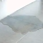 Water pooling on light-colored tile flooring after a plumbing issue at Great Day Plumbing & Air's service site.