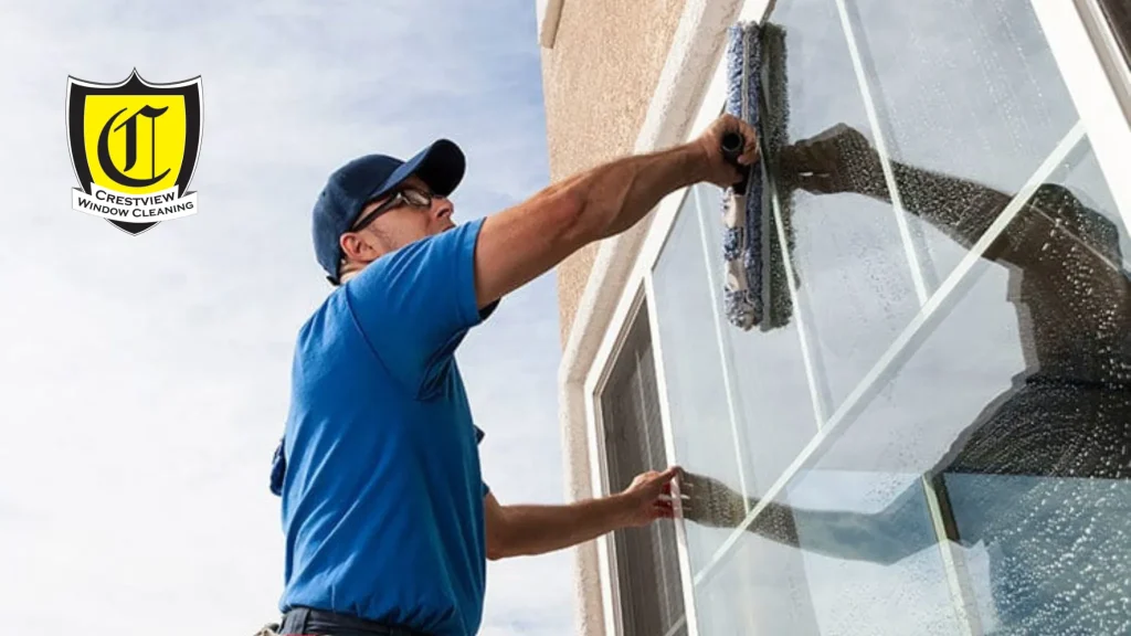 A professional window washer cleaning residential windows in Portland with the Crestview Window Cleaning logo. Searching for window washers near me in Portland can help homeowners achieve streak-free windows.