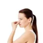 Woman pinching her nose, expressing discomfort, relevant to discussions on electrical safety and odors from outdated electrical panels.