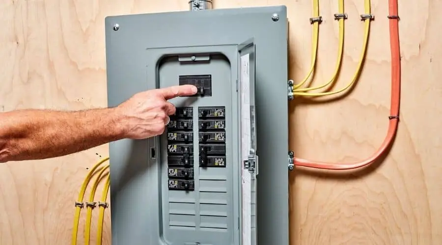 Person pointing at an electrical panel with circuit breakers, highlighting the importance of electrical safety and potential signs for panel upgrades.