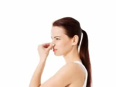 Woman pinching her nose, indicating a bad smell, related to the distinct odor of electrical fires and safety concerns in residential electrical systems.