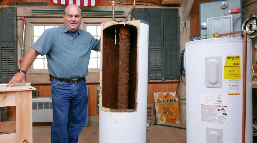 Man next to old and new water heaters in a workshop, highlighting plumbing services by Scott Plumbing for home maintenance.