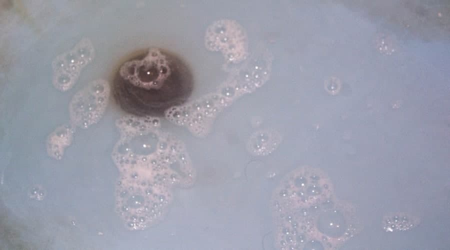Bubbling water in a sink with a visible drain, illustrating potential signs of a sewer line clog as discussed in plumbing maintenance and drain cleaning guidance.