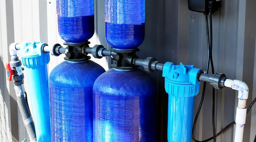 Blue water filtration tanks with piping, showcasing a modern plumbing setup from Scott Plumbing.