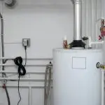 Water heater with metal pipe, white body, and plumbing; part of Quahog Plumbing’s utility solutions in Somerset, MA.