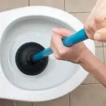 Toilet with plunger showcasing common plumbing maintenance task for Quahog Plumbing services in Somerset, MA.