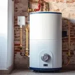 Water heater on exposed brick wall with pipes, showcasing Quahog Plumbing's modern plumbing solutions and efficiency.