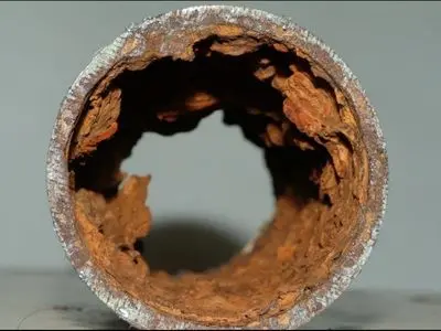 Corroded metal pipe interior showing significant decay and rust buildup, illustrating the effects of corrosion on plumbing systems.