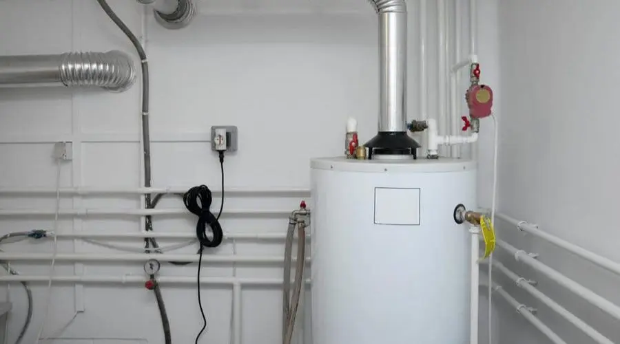 A white, cylindrical water heater with visible pipes and connections in a utility room setting.