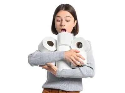 Woman surprised while holding multiple rolls of toilet paper, emphasizing the issue of excessive toilet paper use related to clogged toilets.