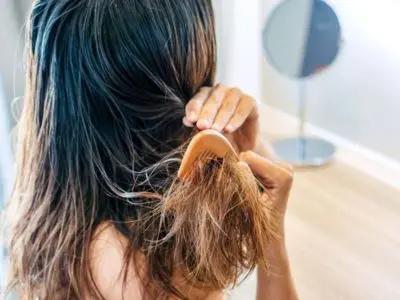 Person combing damp hair, highlighting the impact of water quality on hair health and hydration, relevant to benefits of water softeners for skin and hair.