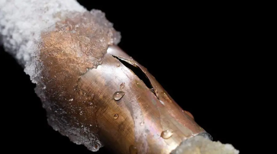 Damaged copper pipe with visible crack and frost, highlighting plumbing vulnerabilities for Quahog Plumbing services.