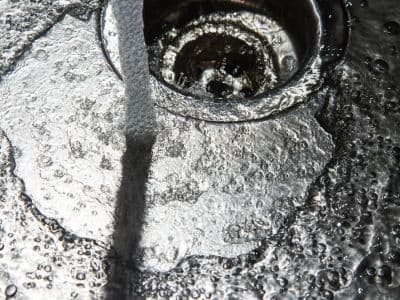 Running cold water and ice in a garbage disposal, highlighting the importance of cold water for maintaining performance and preventing clogs.