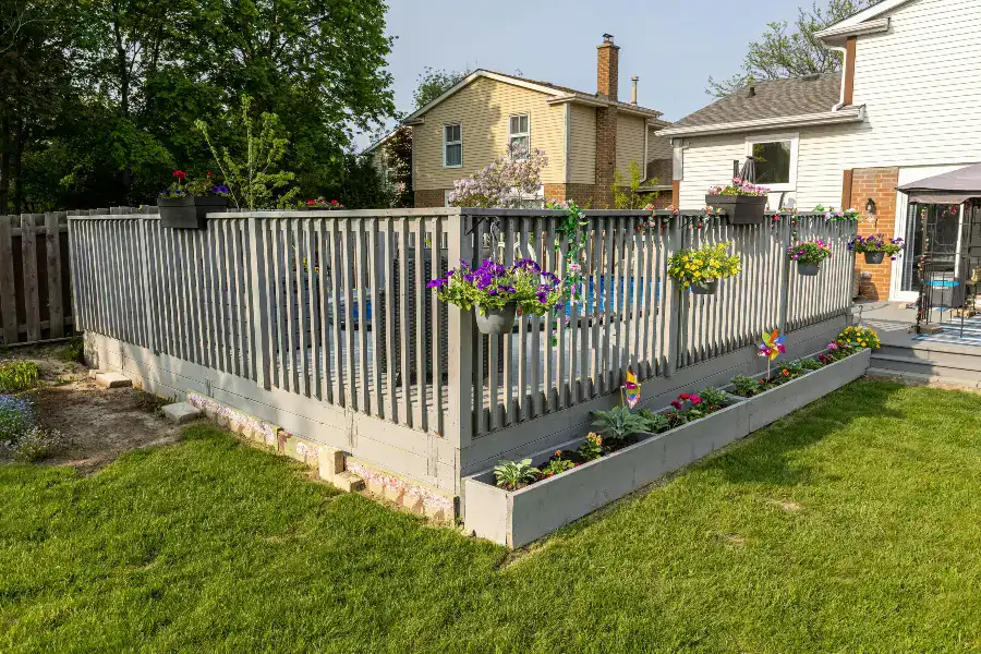Backyard deck with railing, flowers, and landscaping