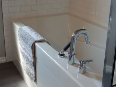 Stylish freestanding bathtub with modern faucet and a soft towel draped over the edge, showcasing a luxurious bathroom renovation concept.