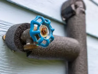 Pipe with blue valve and insulation, demonstrating effective protection against freezing temperatures for plumbing systems.