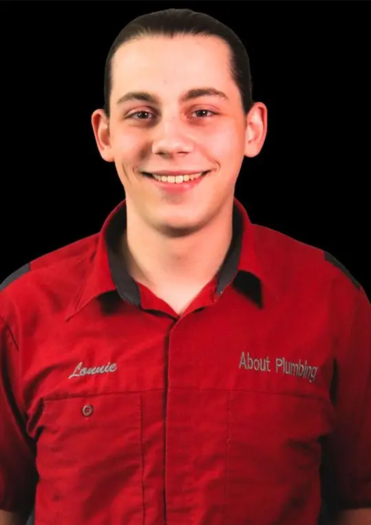 Lonnie Tucker, technician at About Plumbing Inc., wearing a red uniform with company branding.