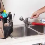 Kitchen sink with modern faucet and tools in a plumbing maintenance setup at About Plumbing Inc.