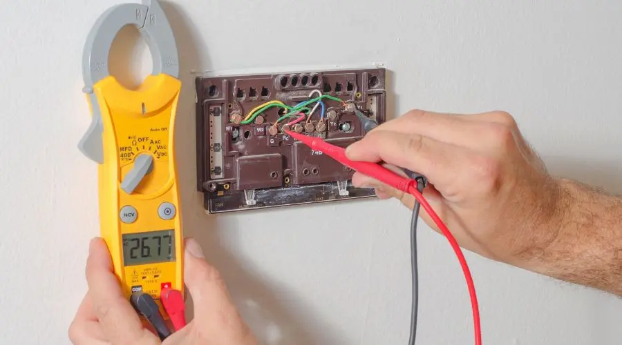 Electric meter and electrical panel used for maintenance by Hancock & Son Plumbing, showing testing leads and green wires.